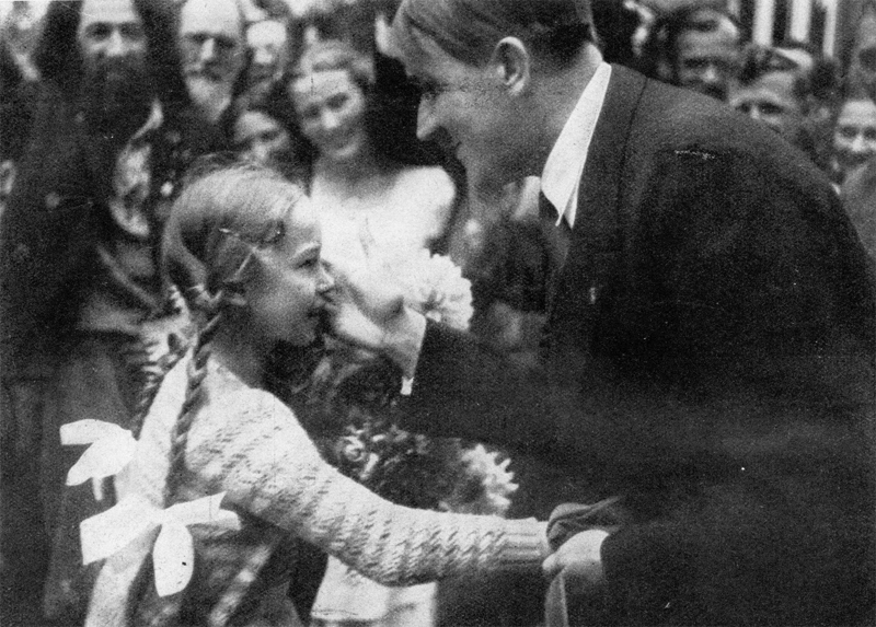 Adolf Hitler is welcomed by a little girl in Oberammergau